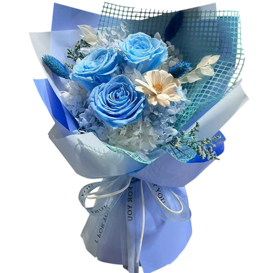 Bouquet of blue roses and white flowers wrapped in blue paper with a ribbon.